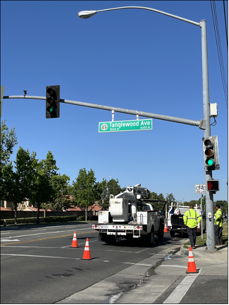 Tanglewood Ave newly installed street sign. On the street are orange cones, a white service truck, and public works staff